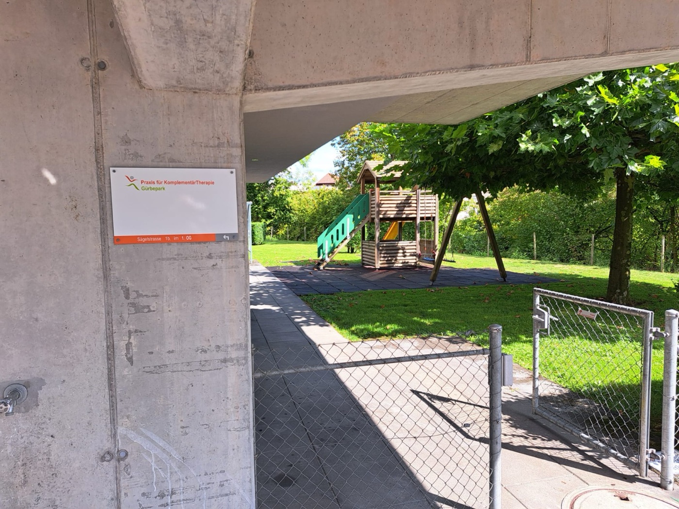 Praxisschild im Durchgang: Praxis für KomplementärTherapie Gürbepark, Sägetstrasse 1b, 1. OG — Pfeil folgen